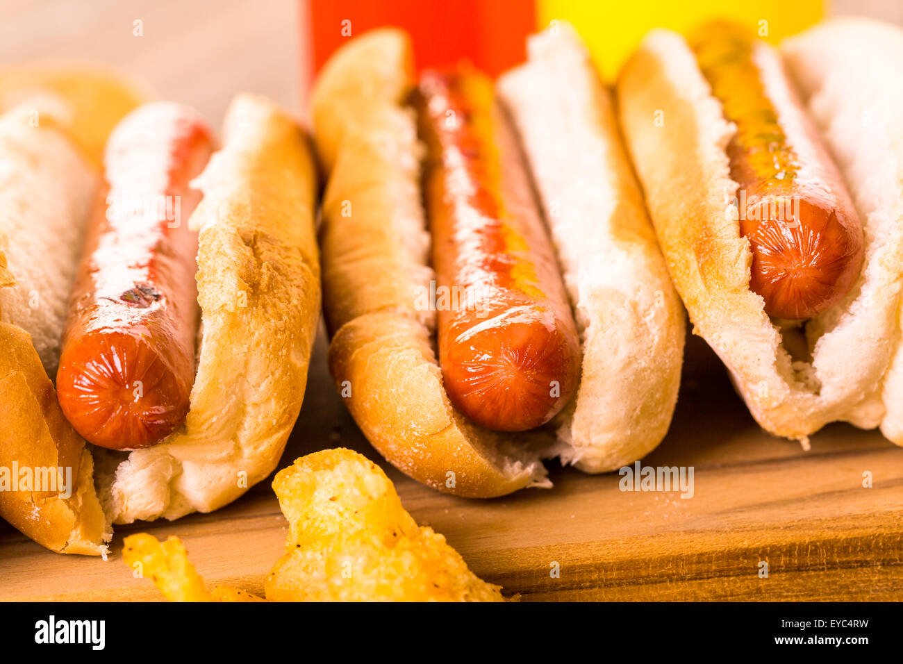 Grilled hot dogs on a white hot dog buns with chips and baked beans on