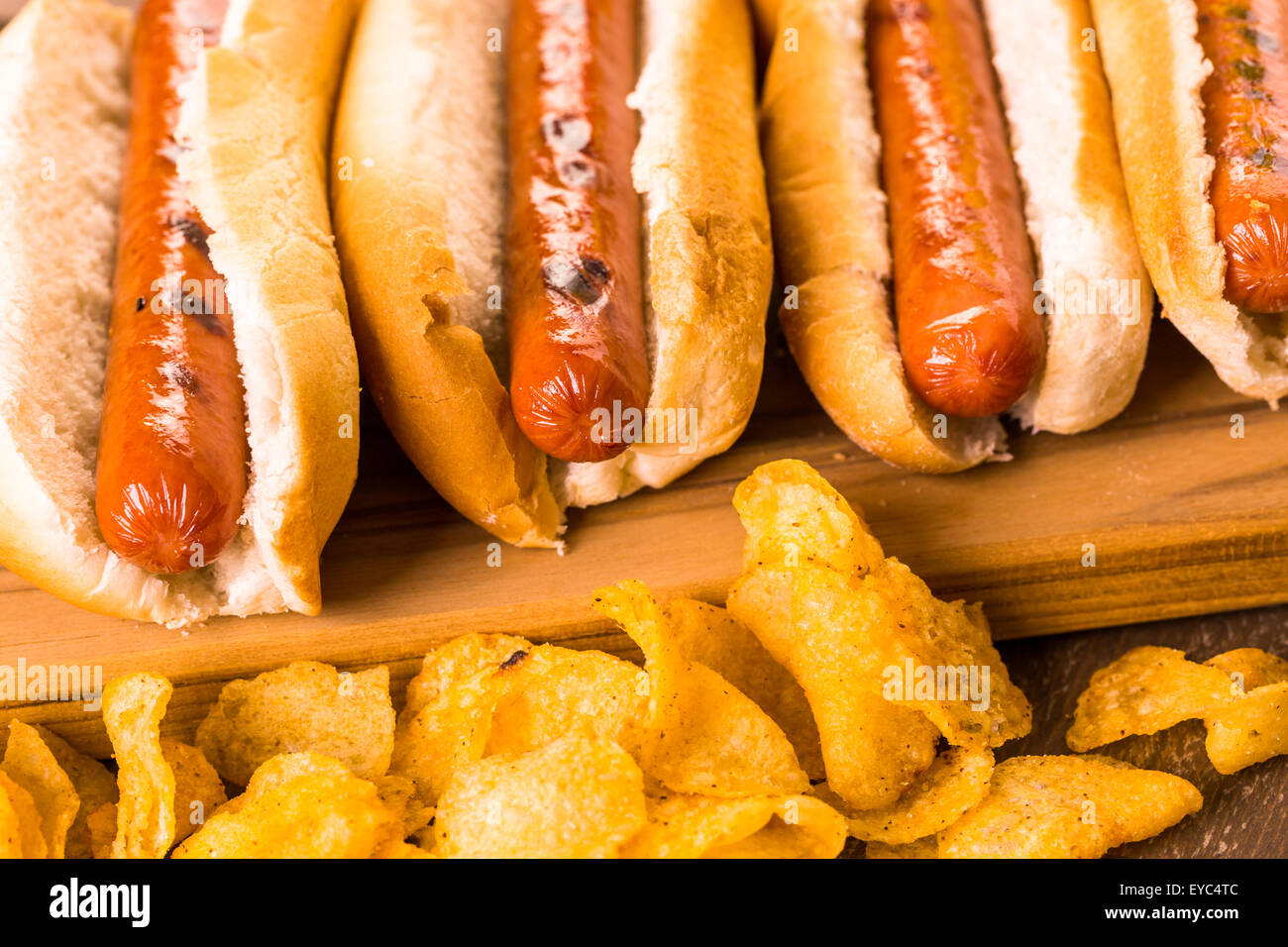 Grilled hot dogs on a white hot dog buns with chips and baked beans on