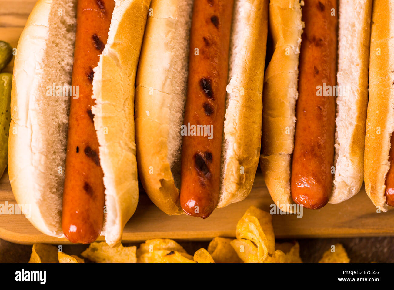 Grilled hot dogs on a white hot dog buns with chips and baked beans on