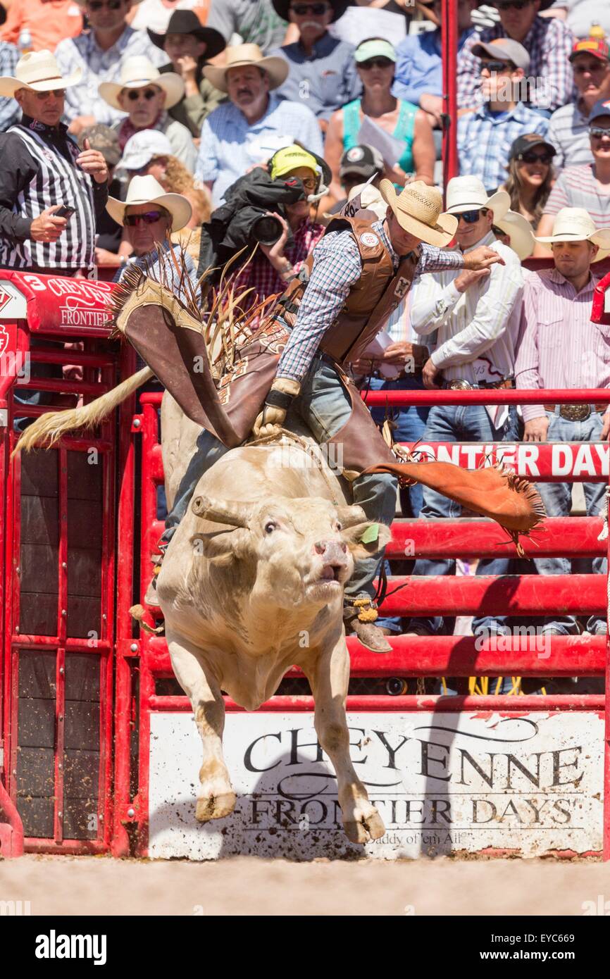 Cheyenne, Wyoming, USA. 26th July, 2015. Bull rider Caleb Sanderson hangs on during the Bull Riding finals at the Cheyenne Frontier Days rodeo in Frontier Park Arena July 26, 2015 in Cheyenne, Wyoming. Frontier Days celebrates the cowboy traditions of the west with a rodeo, parade and fair. Stock Photo