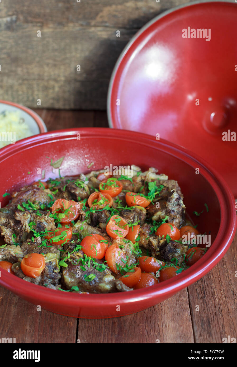 Moroccan tagine with lamb, tomatoes and couscous on a wooden table