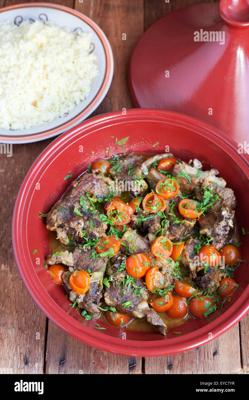 Moroccan tagine with lamb, tomatoes and couscous on a wooden table