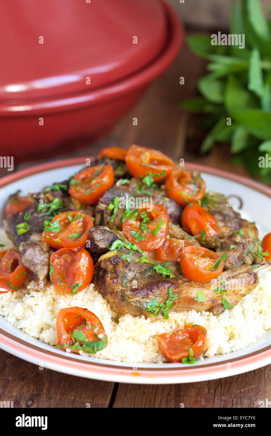 Moroccan tagine with lamb, tomatoes and couscous on a wooden table. Selective focus. Stock Photo