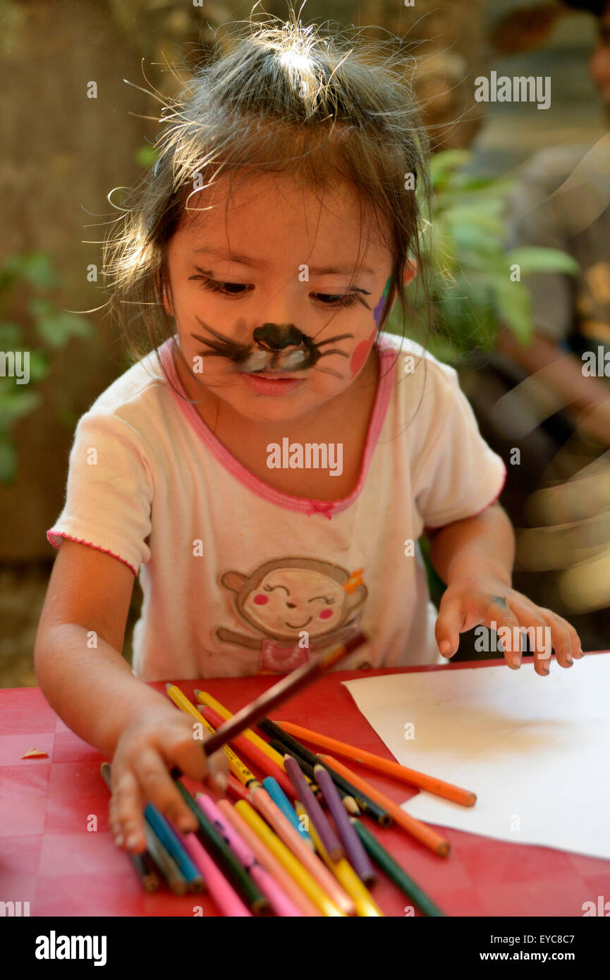 Girl with face painted as a cat drawing at a children's festival, a peace initiative by the police and the Catholic Church in Stock Photo