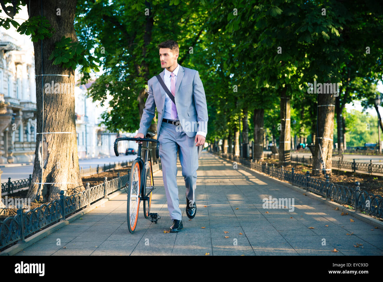 Handsome businessman walking with bicycle on the street in town Stock Photo