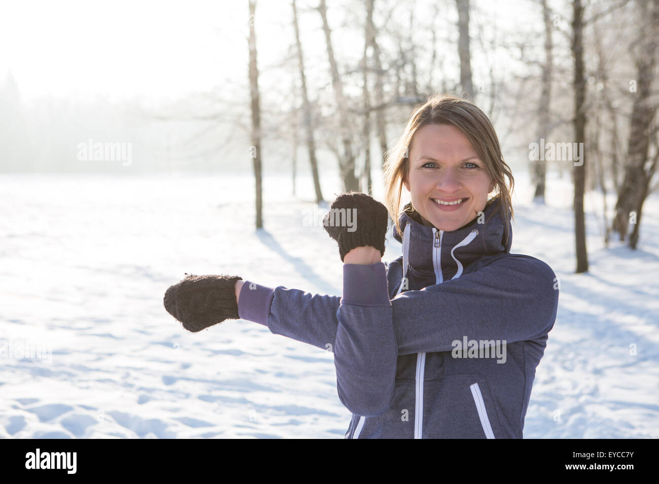 Young woman stretching in snow Stock Photo