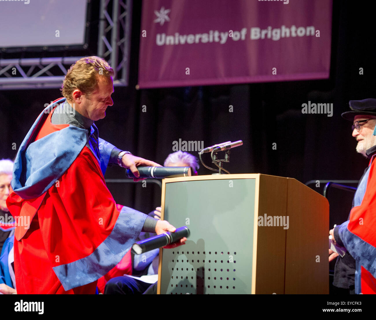 Brighton, UK. 27th July, 2015. Summer graduations at the University of Brighton. Luke Cresswell (left) and Steve McNicholas (right) the founders of Stomp were awarded honorary degrees as Doctor of Arts at the ceremony held this mornining at the Dome in Brighton. The pair celebrate using their scrolls as percussion sticks on the podium in their acceptance speach. Credit:  Jim Holden/Alamy Live News Stock Photo
