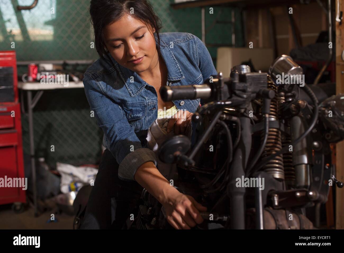 Female mechanic working on motorcycle in workshop Stock Photo