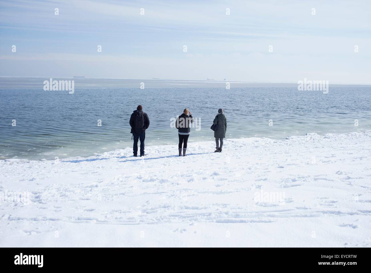 Three adults looking out to sea, Fairfield, Connecticut, USA Stock Photo
