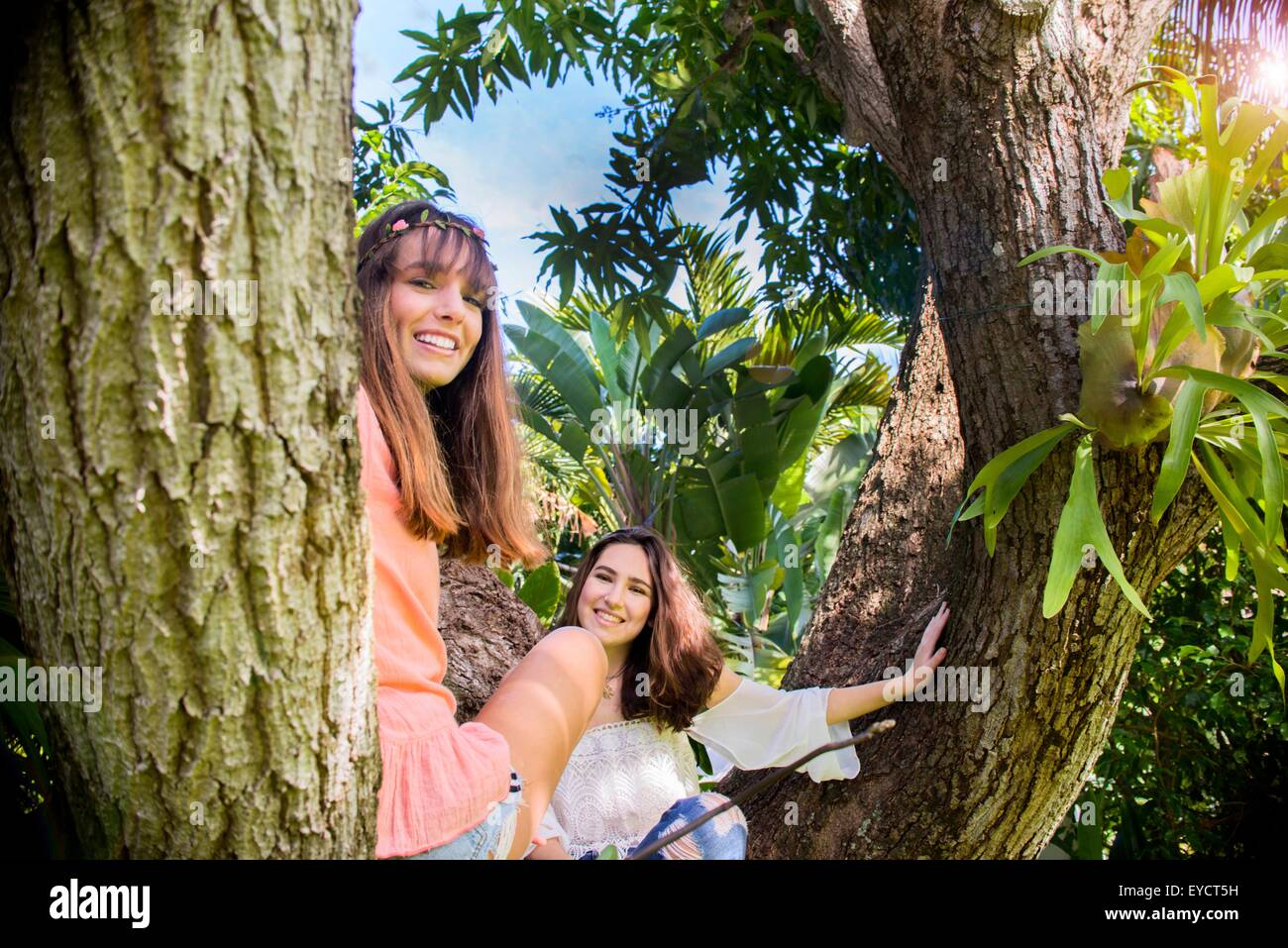 Portrait of two young female friends sitting in tree Stock Photo