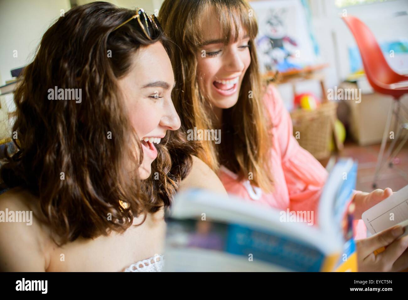 Two young female friends browsing and laughing at books Stock Photo