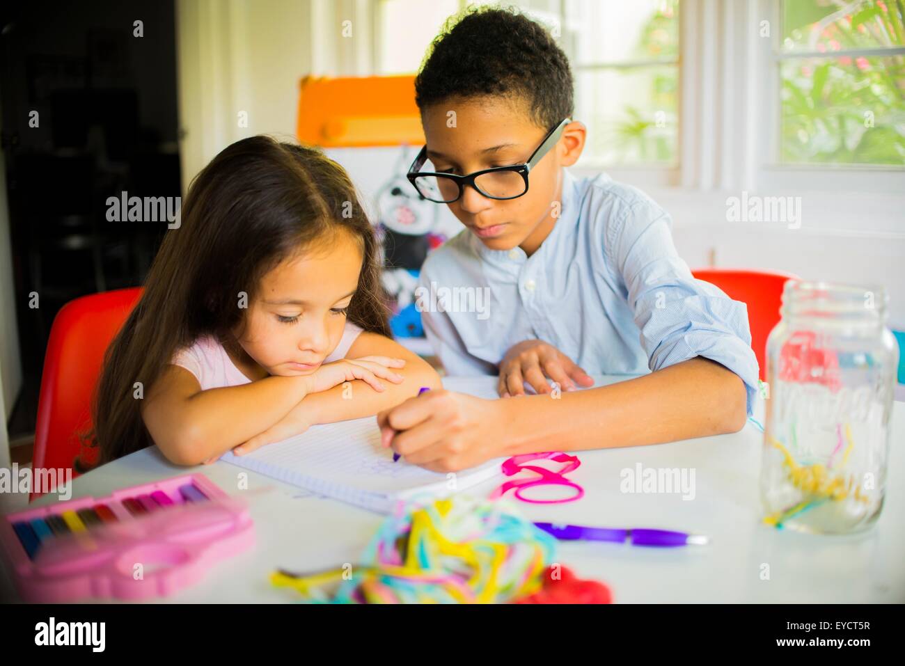 Boy and girl crayon drawing at kitchen table Stock Photo