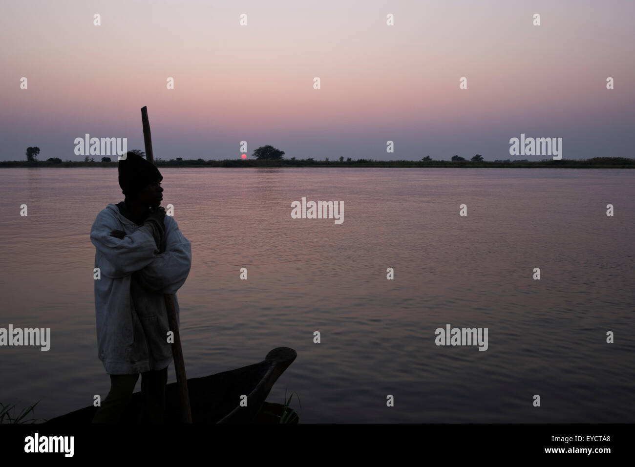 An African fisherman paddles his canoe or makoro on the Zambezi river Zambia at sunrise. Stock Photo
