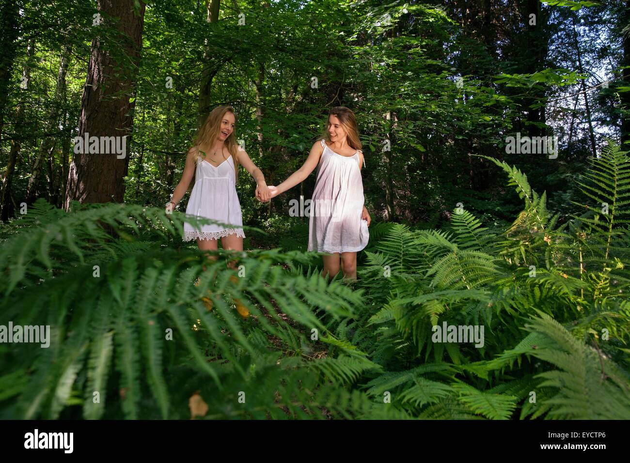 Two teenage girls walking through forest, hand in hand Stock Photo