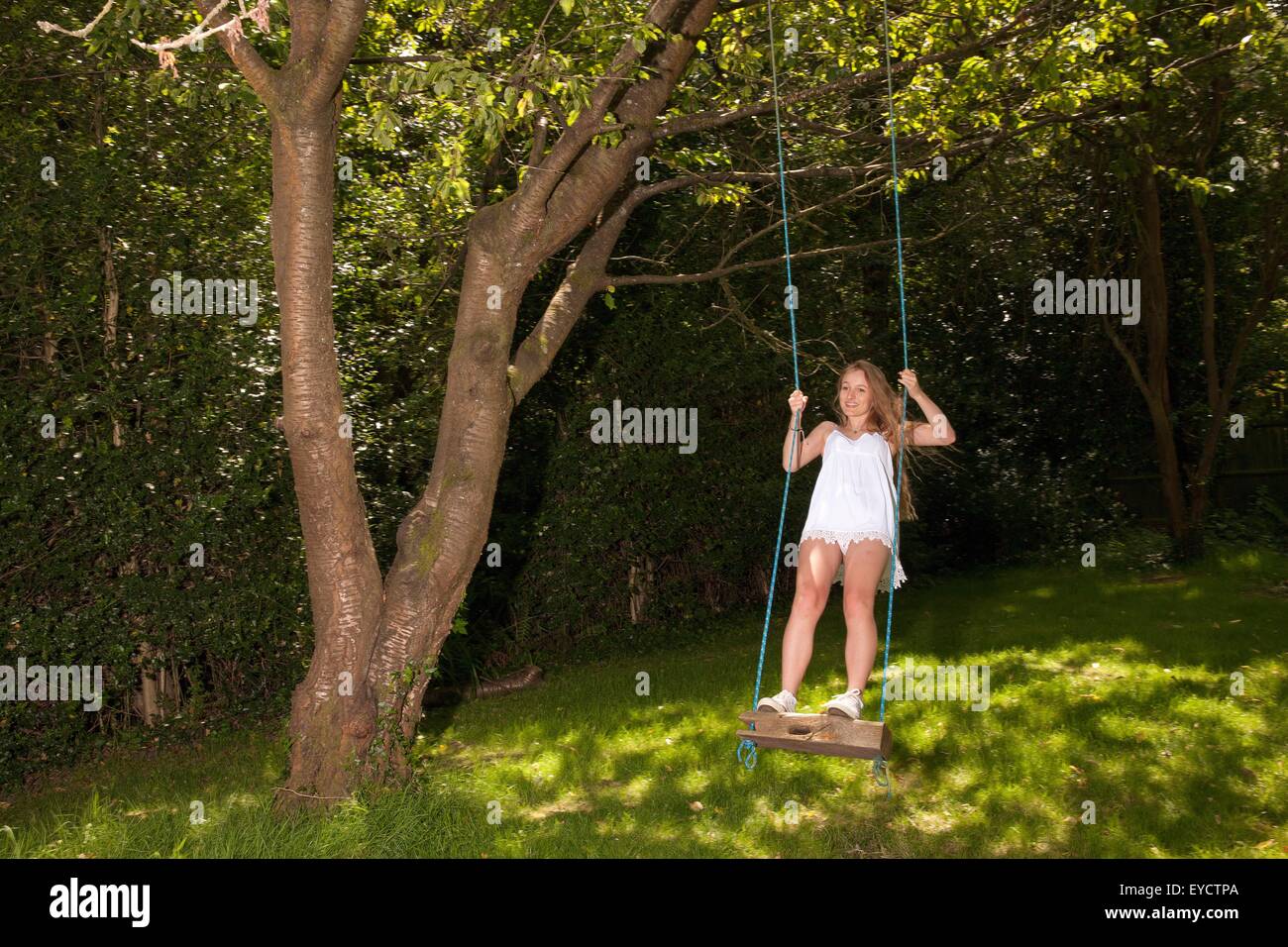 Teenage girl swinging on tree swing Stock Photo