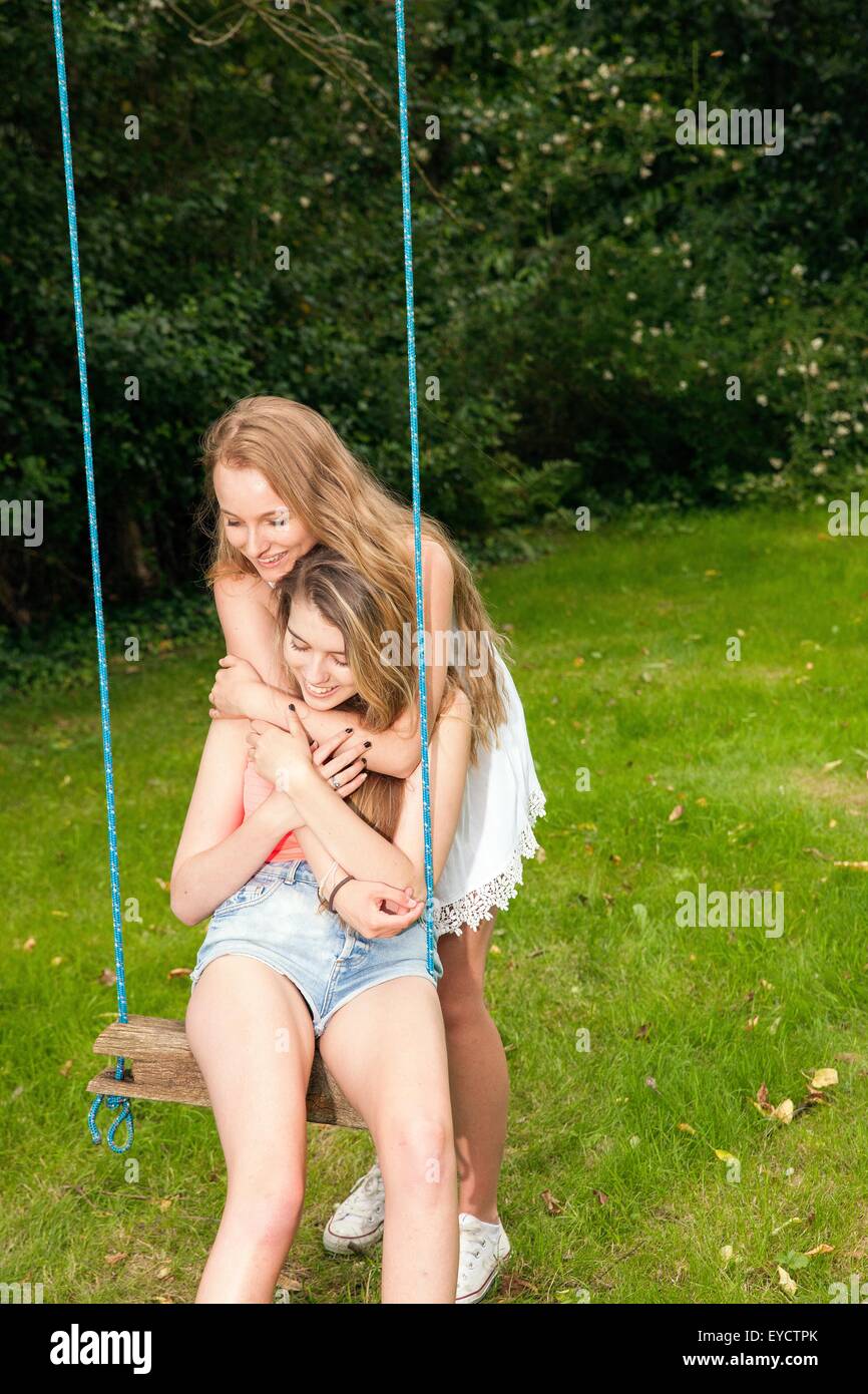 Two teenage girls playing on swing Stock Photo