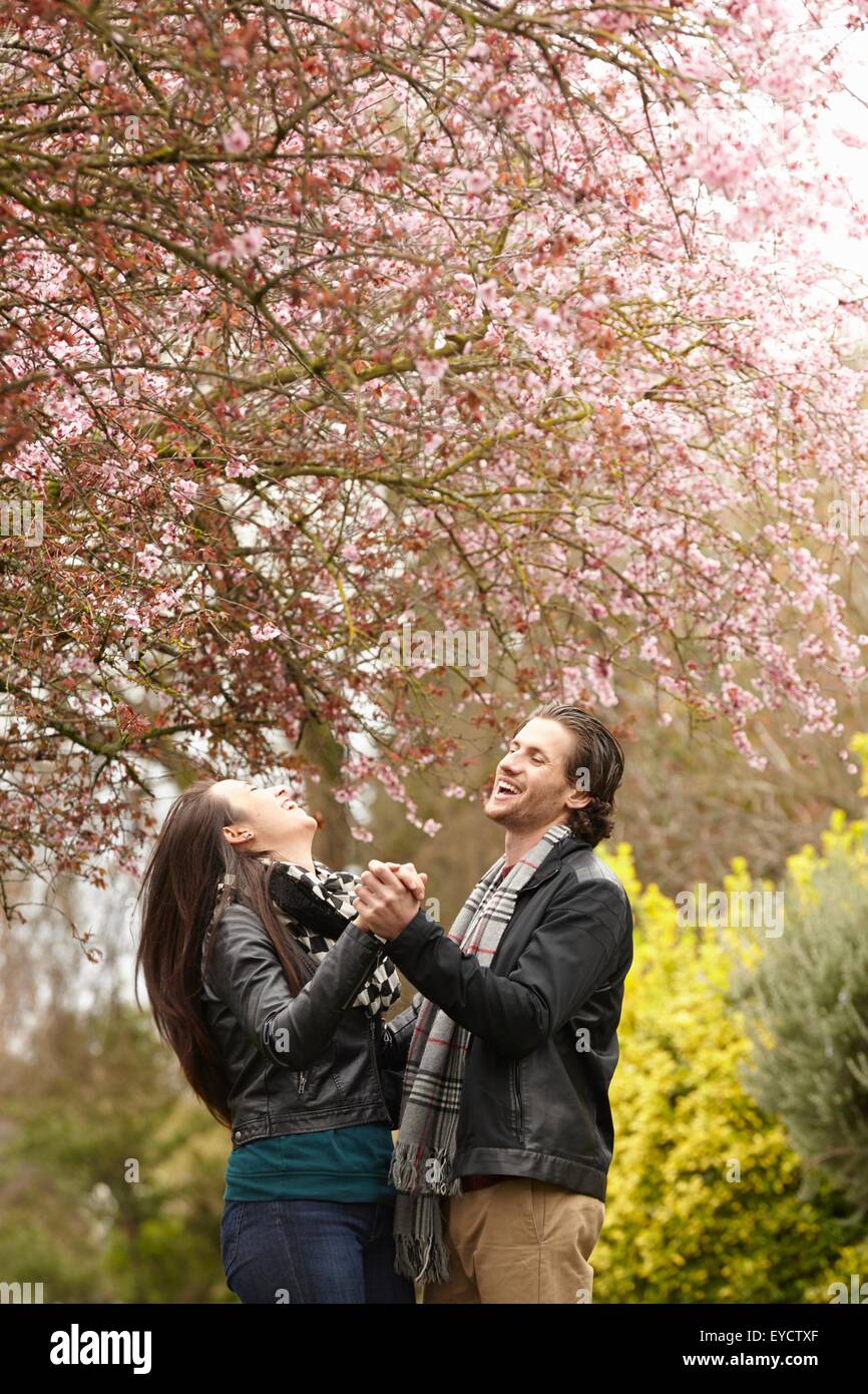Young couple dancing under blossom in park Stock Photo