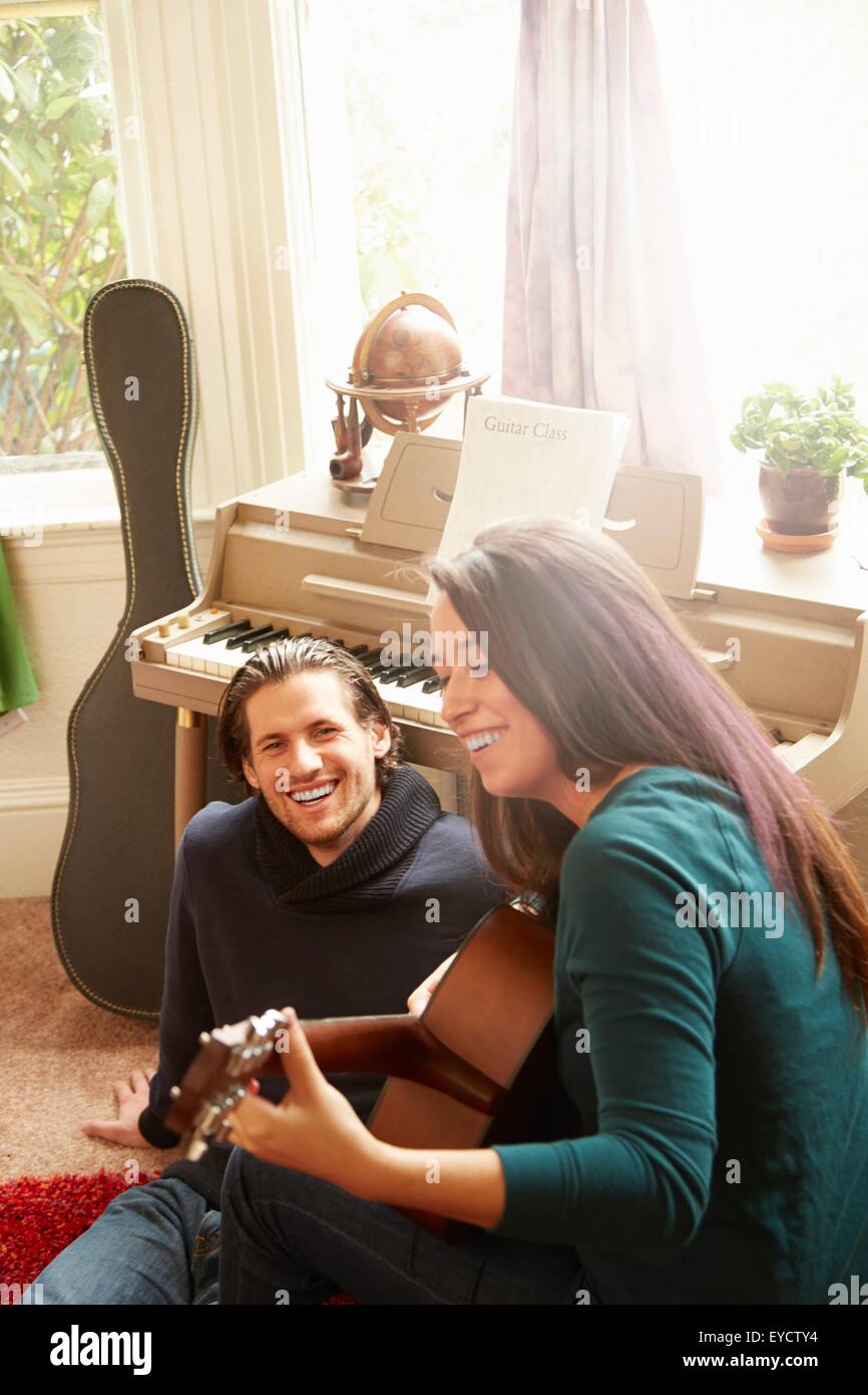 Young couple playing acoustic guitar in living room Stock Photo