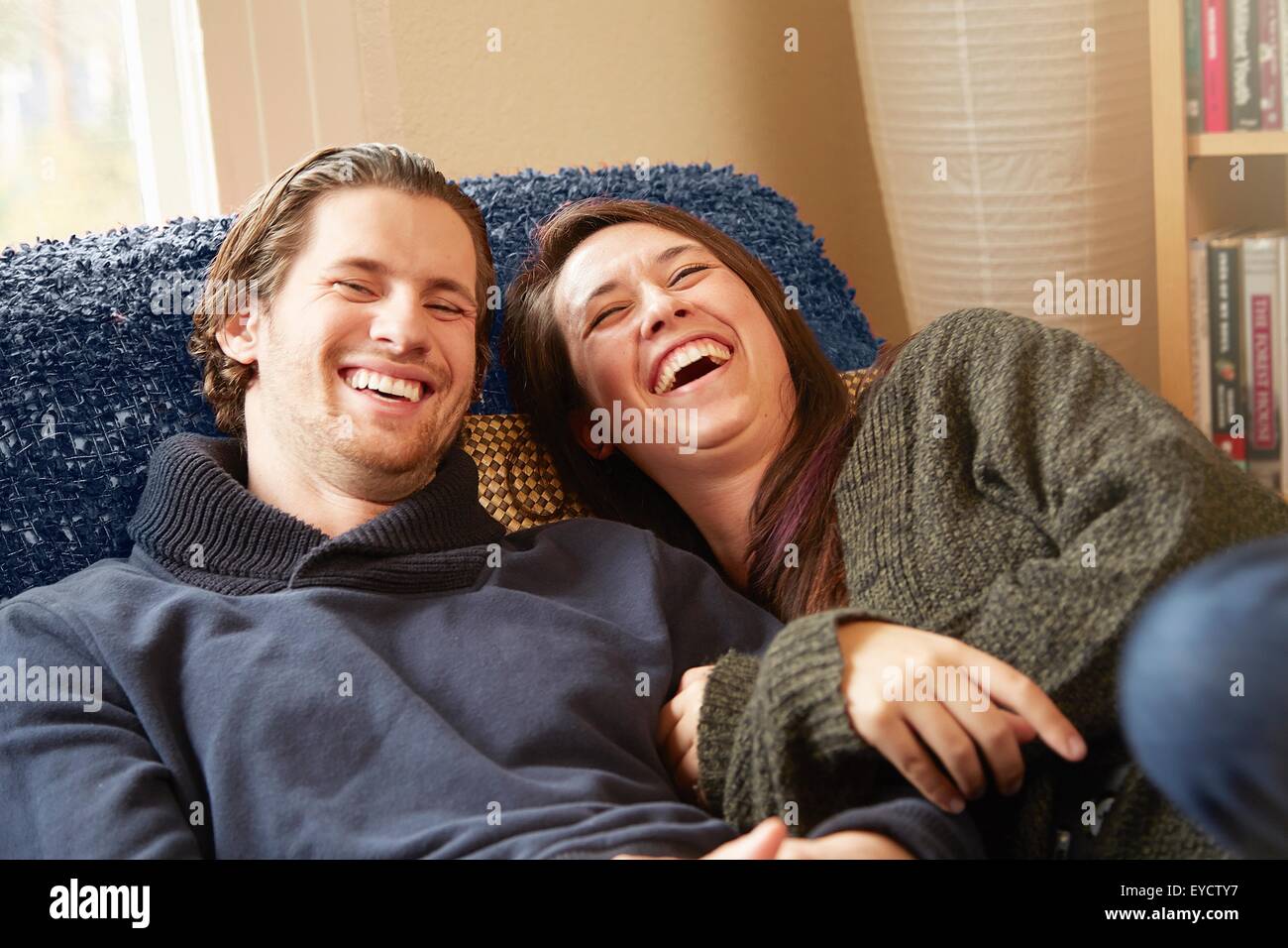 Young couple laughing on living room sofa Stock Photo