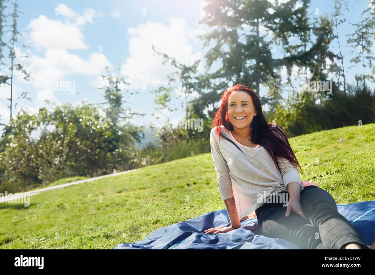 Young woman sitting on picnic blanket in park Stock Photo