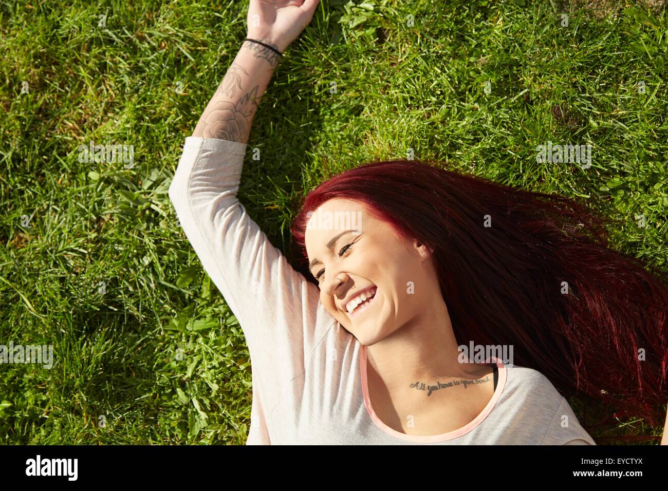Overhead view of young woman lying on grass laughing Stock Photo