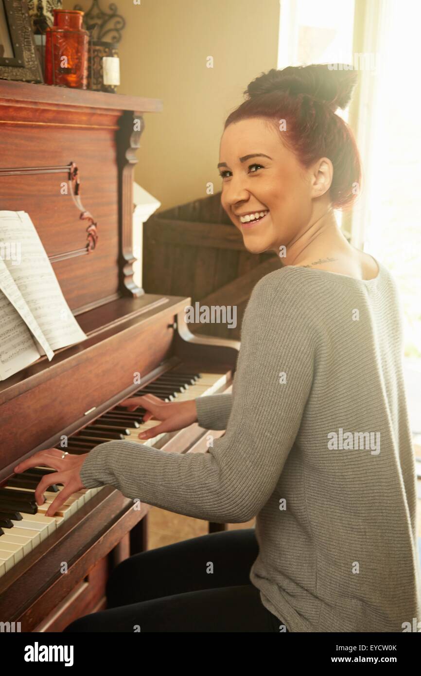 Young woman playing piano in living room Stock Photo