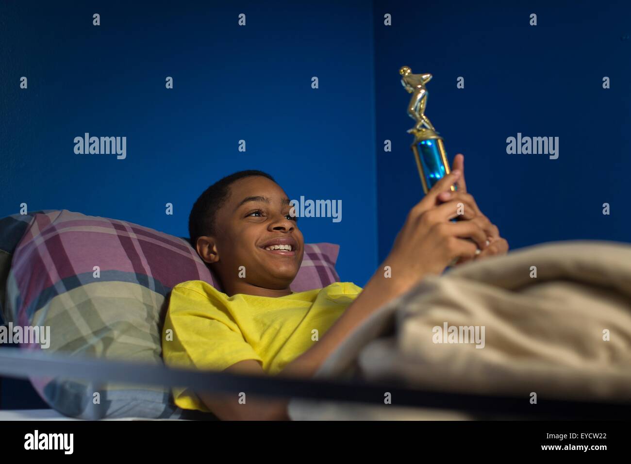 Teenage boy lying in bunkbed admiring trophy Stock Photo
