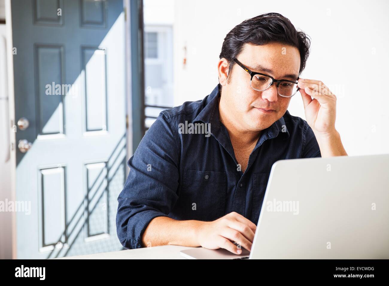 Mature businessman concentrating on laptop in kitchen Stock Photo