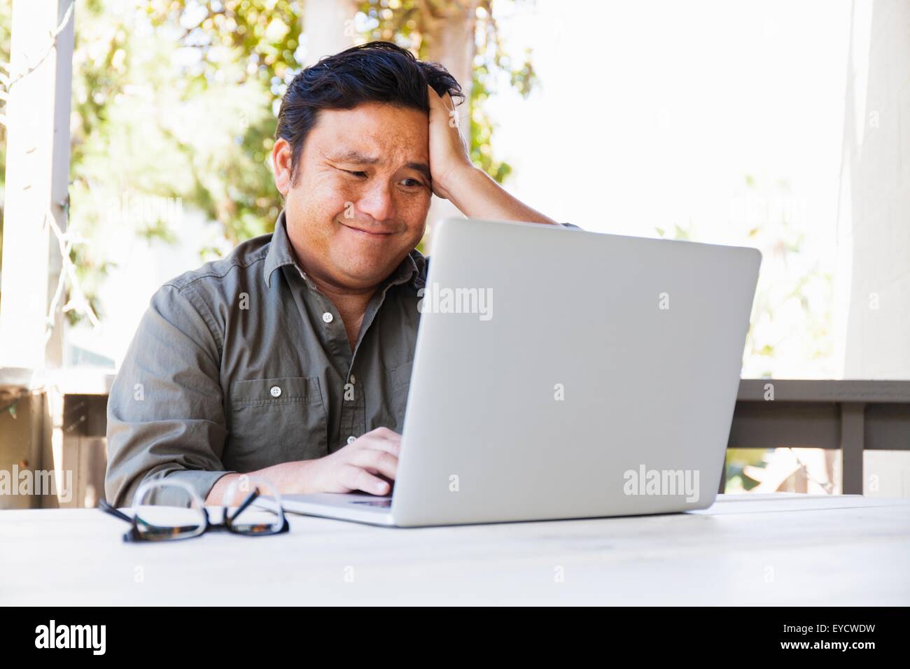 Frustrated mature businessman working on laptop in porch Stock Photo