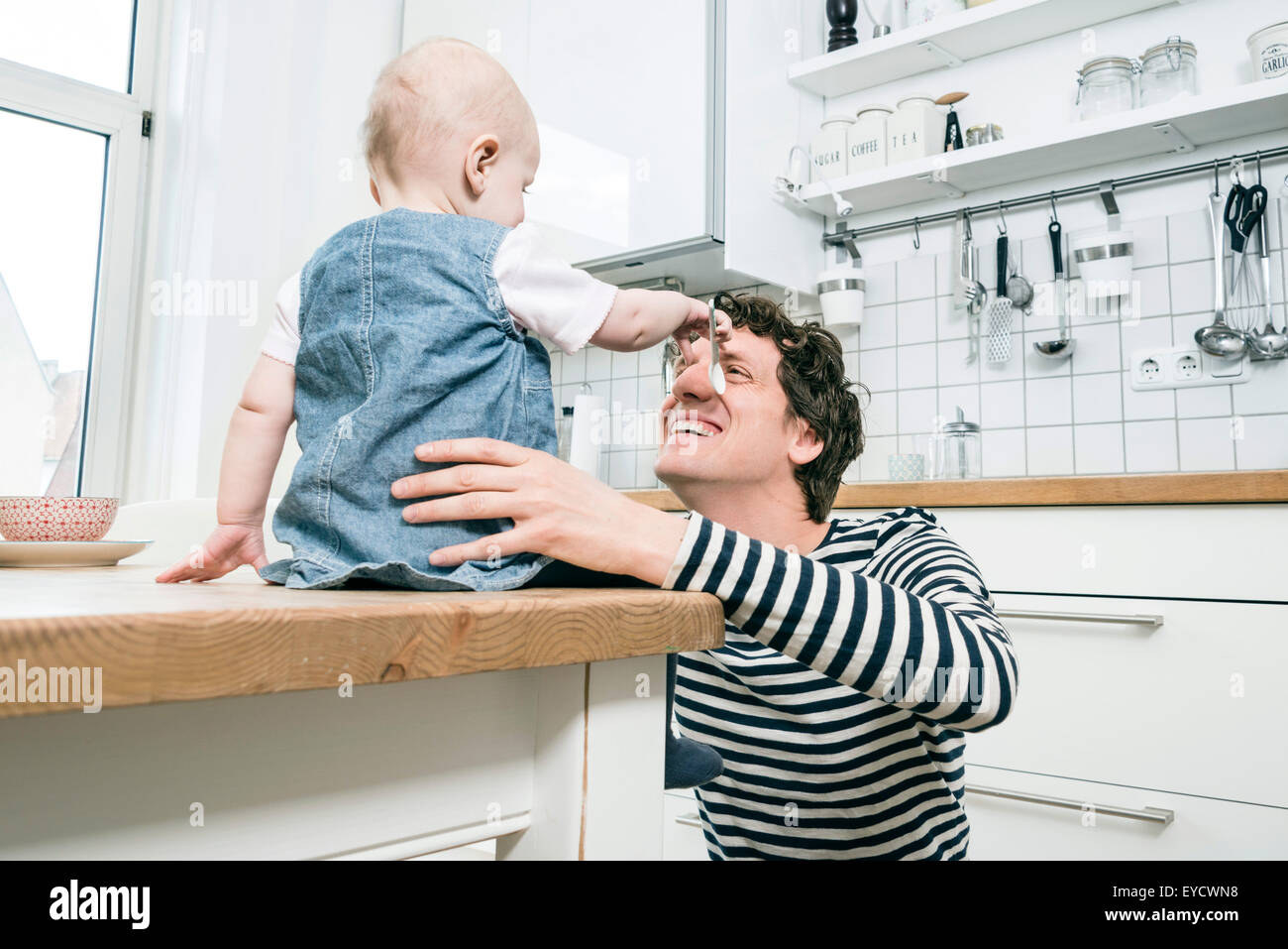 Father playing with baby boy in kitchen Stock Photo