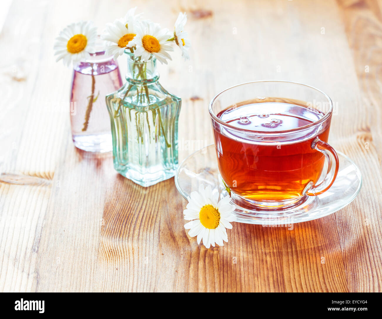 Glass cup of tea with chamomile flowers on rustic wooden background ...
