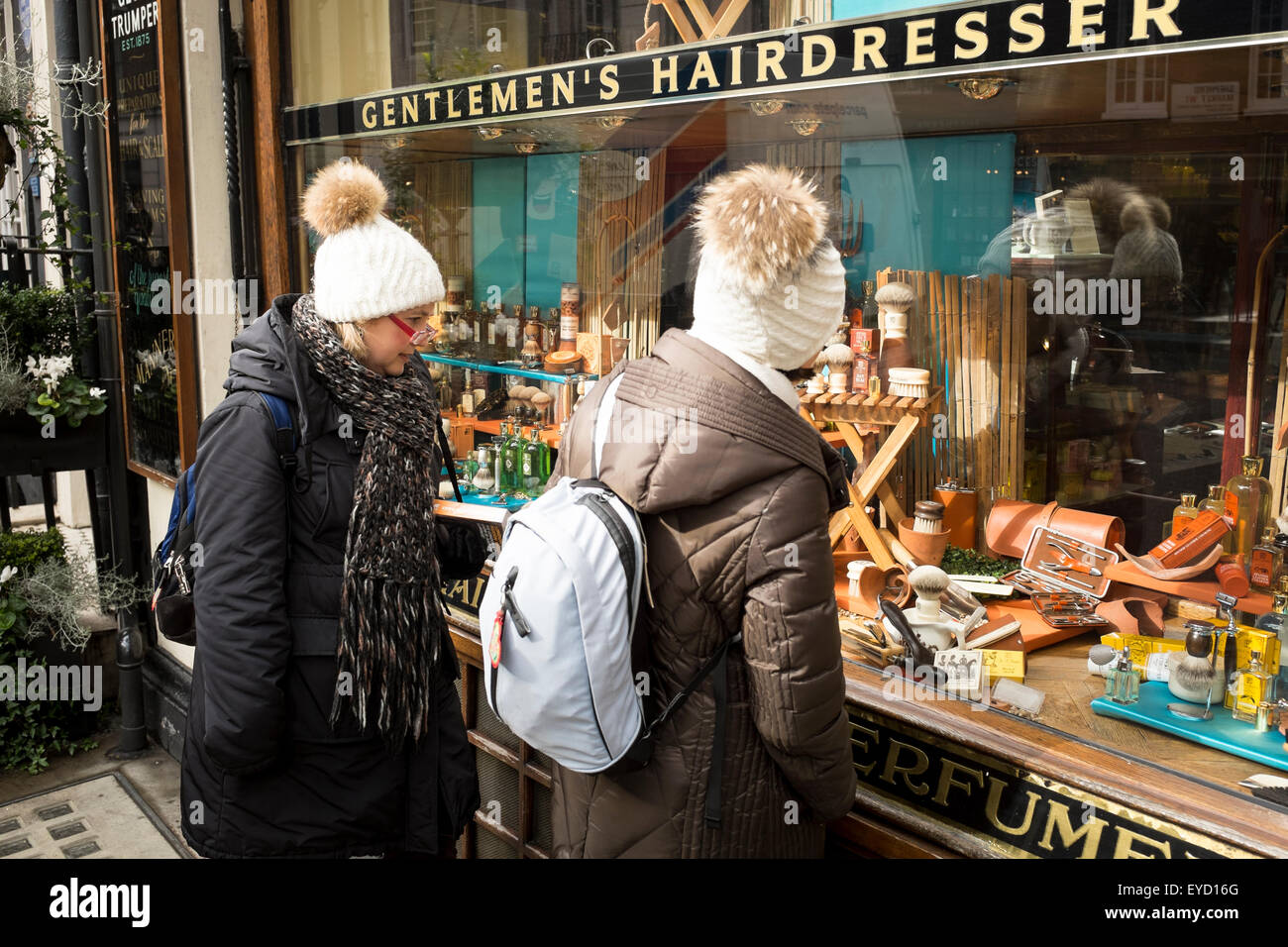 Two female trouist look at the window display by G F Trumper, a traditional barbershop, in Mayfair, London, UK Stock Photo