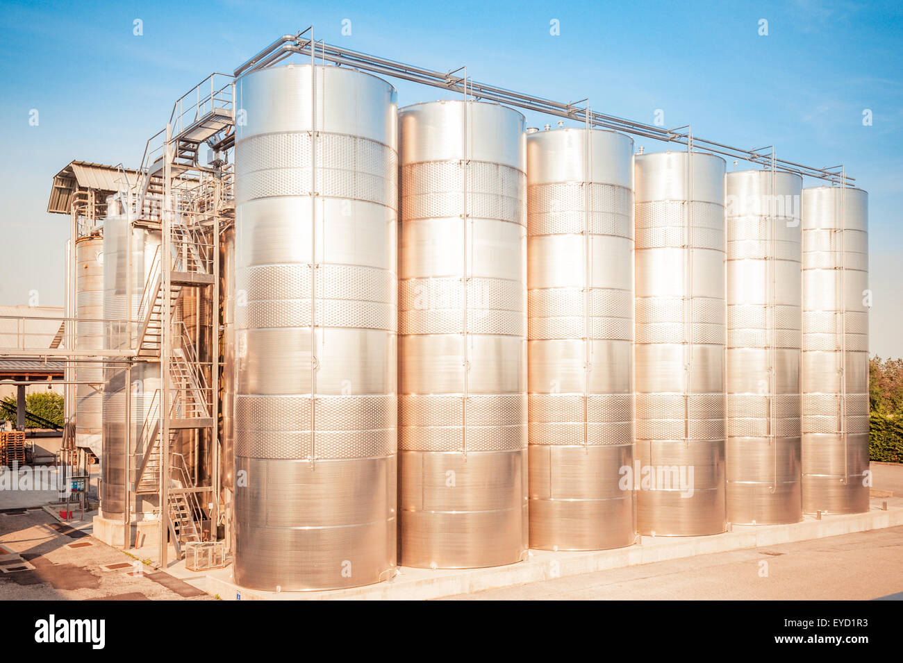 Industrial plant for storing wine, with stainless steel containers, at the sunset sun Stock Photo