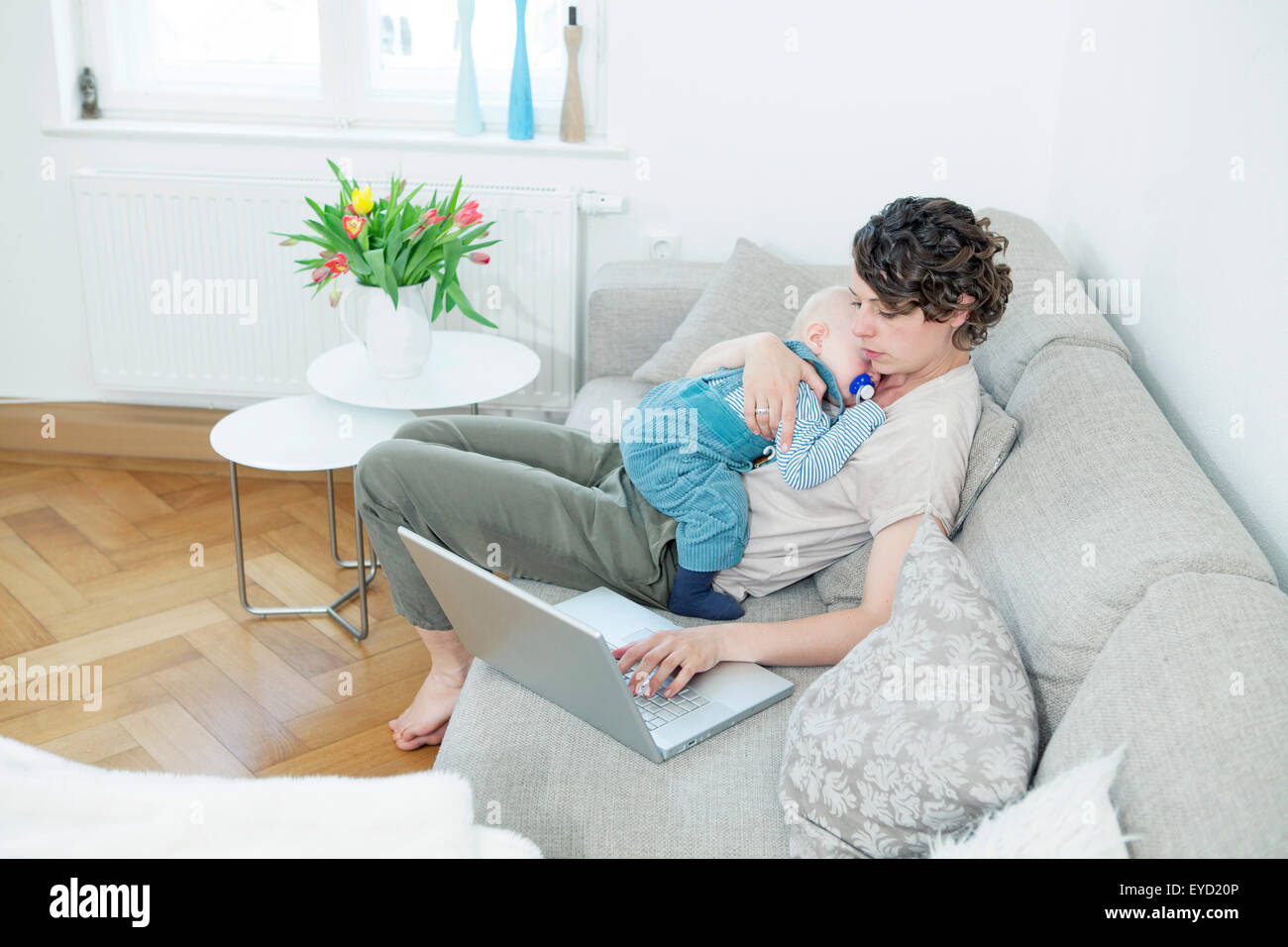 Mother working on laptop with baby in her lap Stock Photo