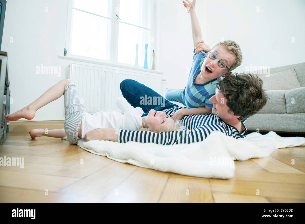 Father playing with two children in living room Stock Photo