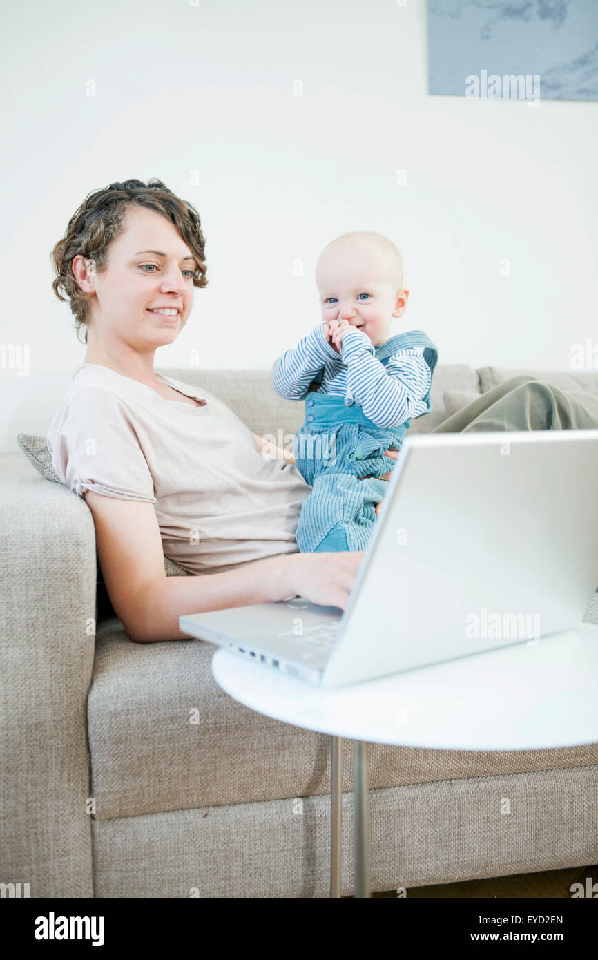Mother working on laptop with baby in her lap Stock Photo