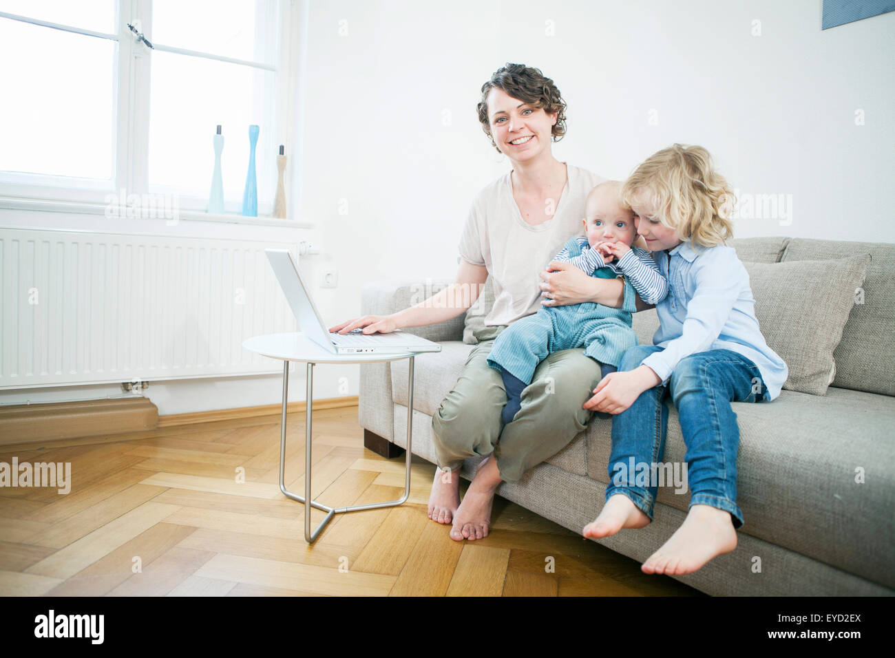 Mother and children with laptop in living room Stock Photo - Alamy