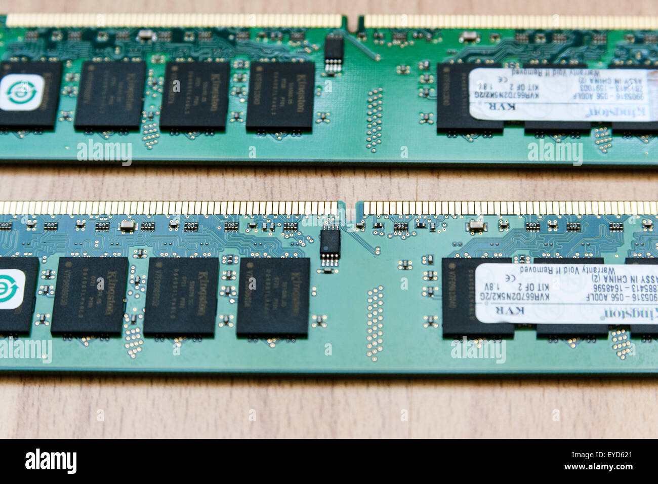 Home computer. Two green DIMM Ram sticks on wooden background. Close up showing black processors and gold coloured connection pins. Stock Photo