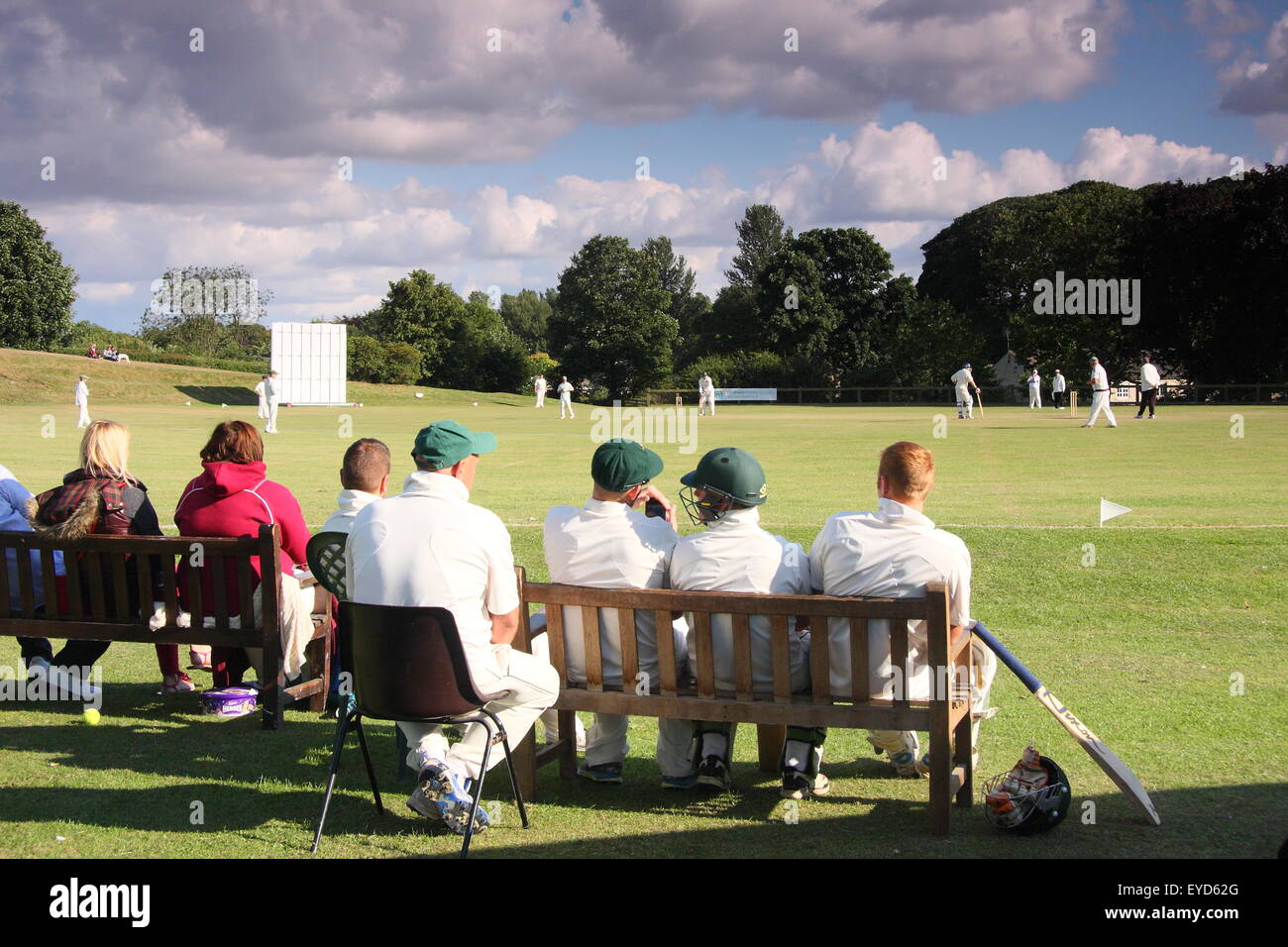 Cricketers watch theri team mates compete in a match in a Yorkshire village near Rotherham, England UK Stock Photo