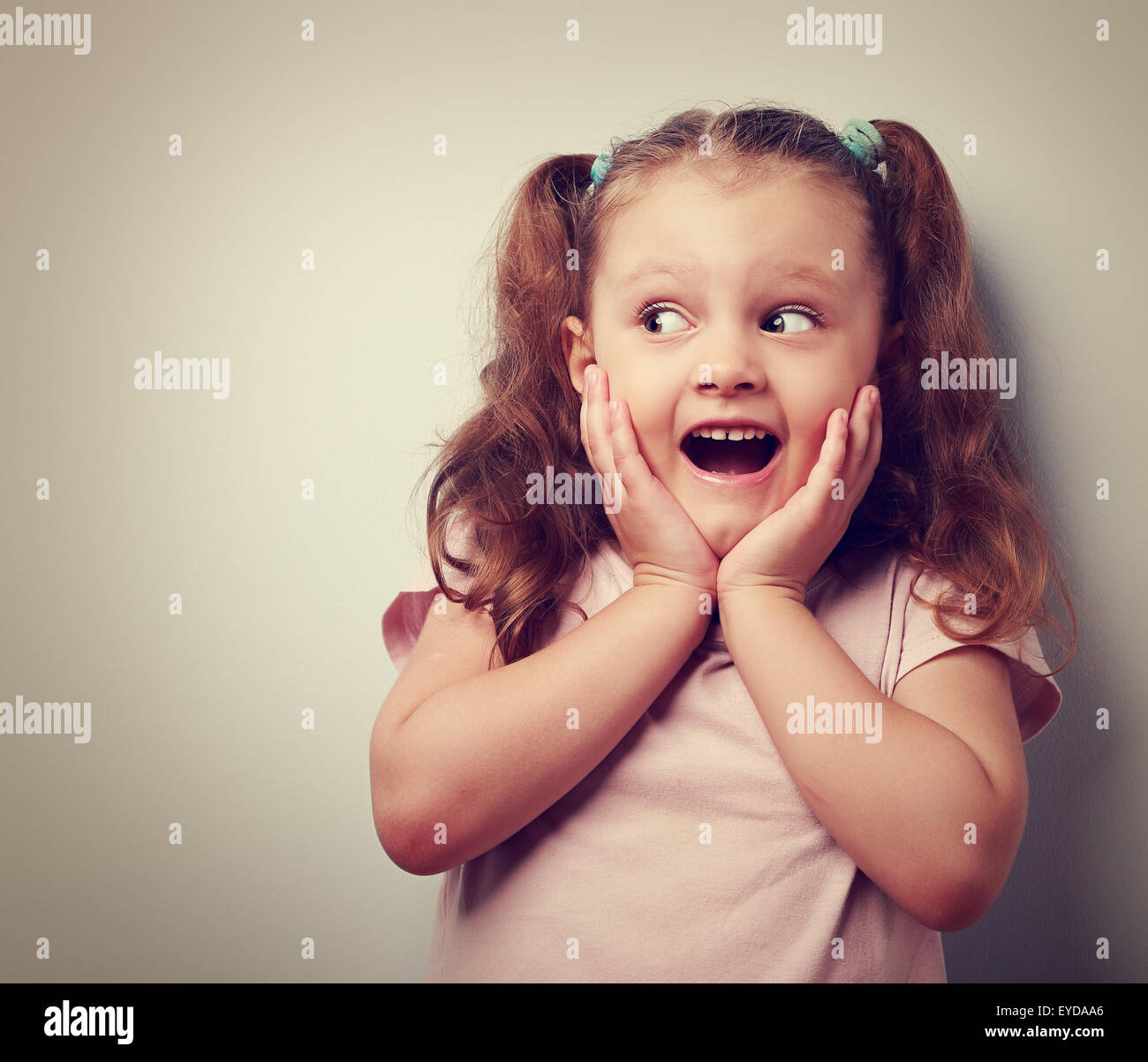 Fun surprising kid girl with open mouth looking on empty copy space. Vintage closeup portrait Stock Photo