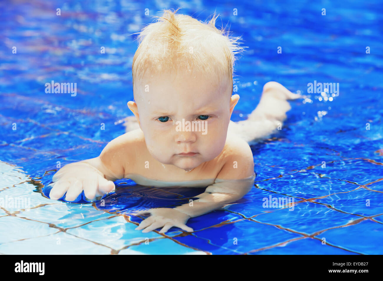 Little baby learning to swim underwater in a swimming pool hires stock