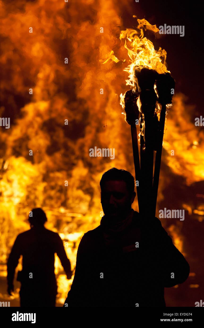 Silhouettes Of People Preparing To Throw Burning Torches On Large Bonfire At Barcombe Bonfire Night, Barcombe, East Sussex, Uk Stock Photo