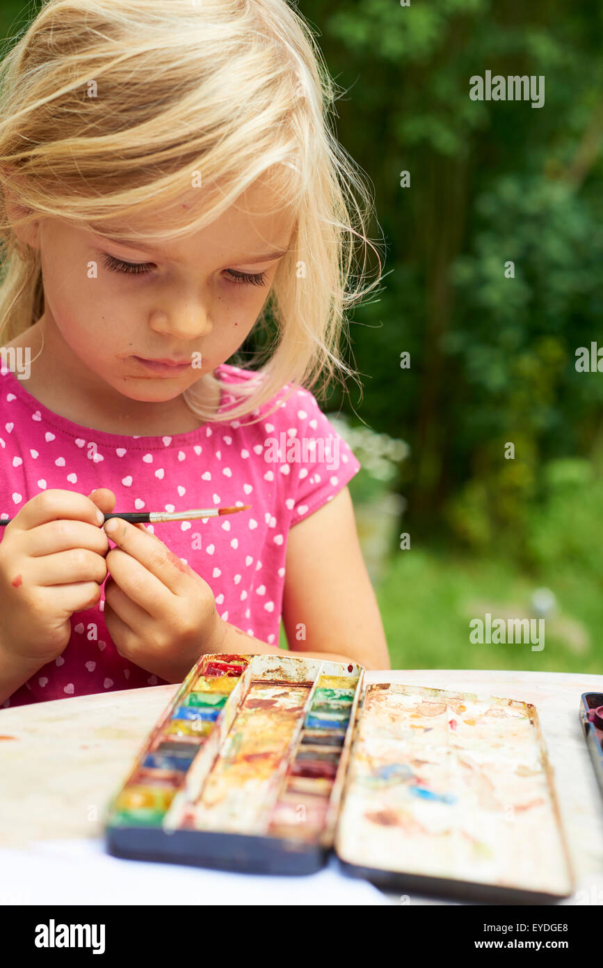 A girl painting with water colours (watercolors), painting a paper ...