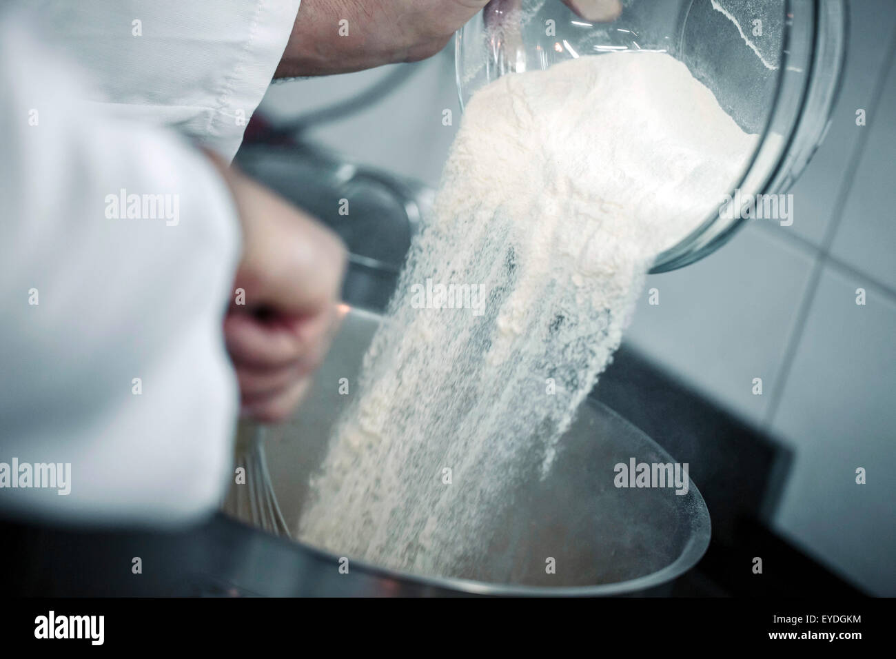 Pouring sugar into metal bowl Stock Photo