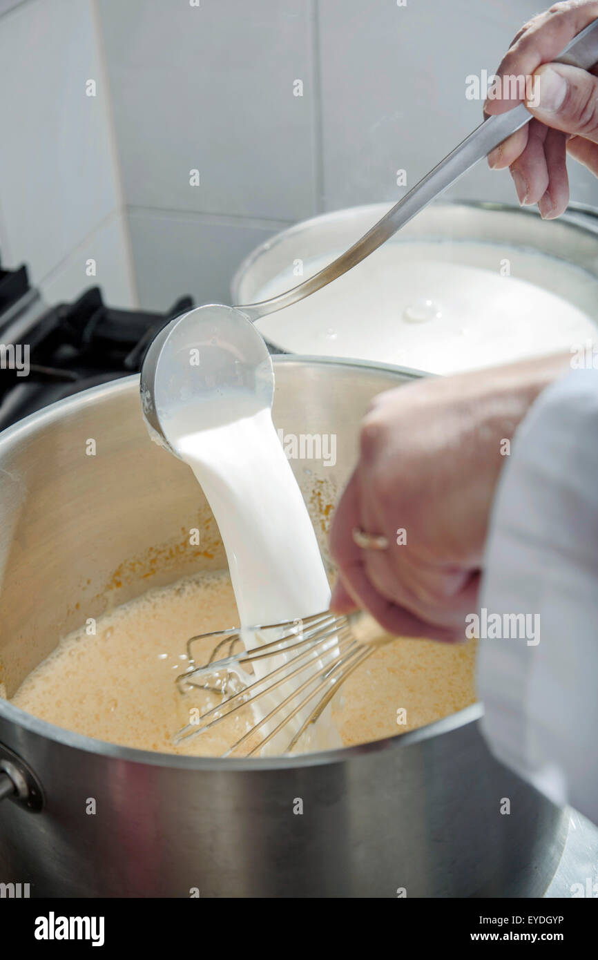 Pouring milk into metal bowl Stock Photo