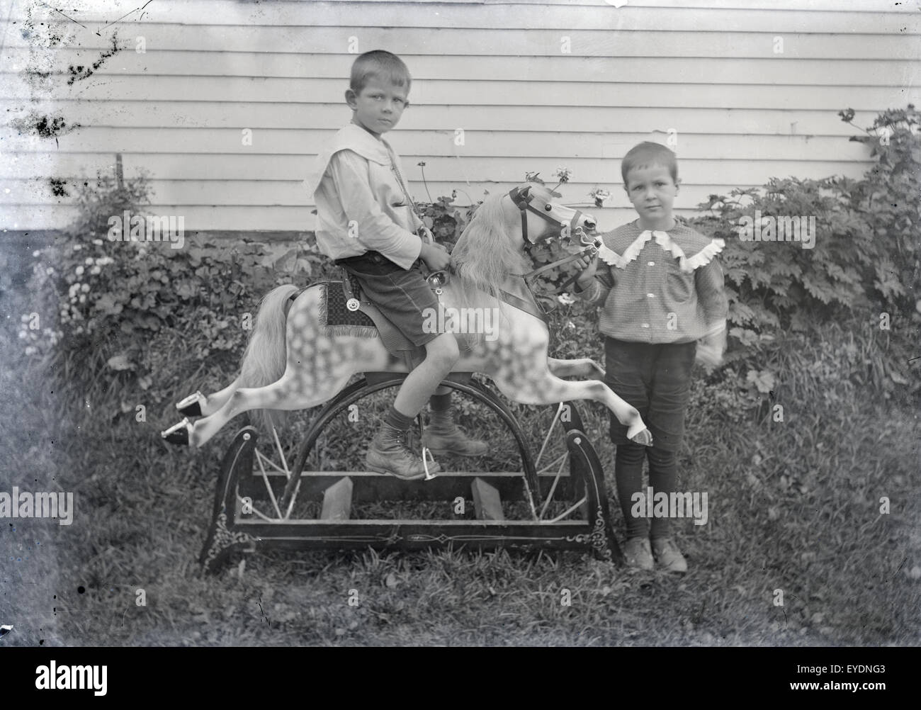 Antique c1900 photograph of two boys, probably brothers or twins, showing off their new Victorian rocking horse. Location is USA. Stock Photo