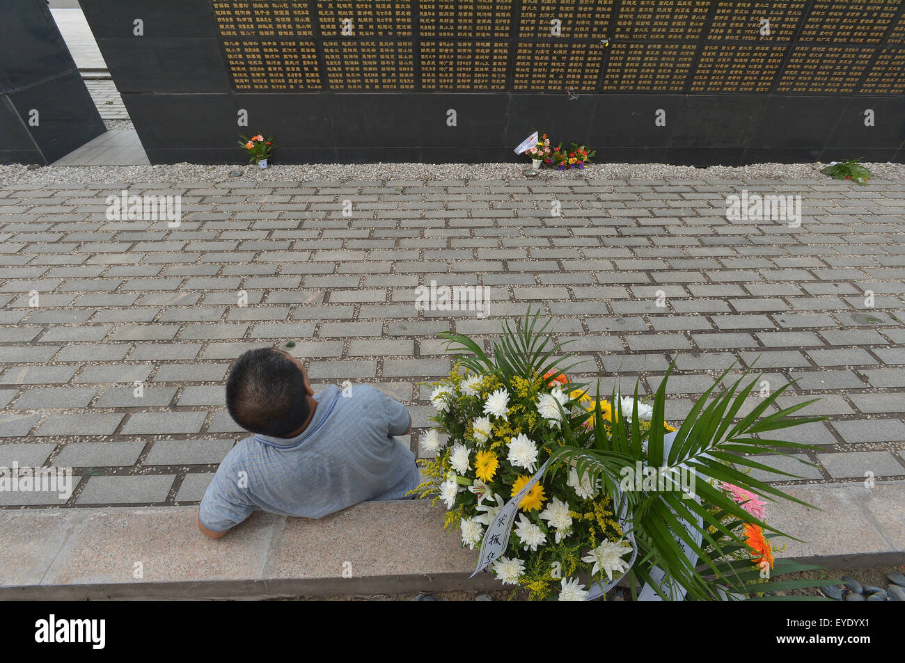 Tangshan, China's Hebei Province. 28th July, 2015. A man mourns for relatives dead in the 1976 Tangshan earthquake in front of the memorial wall in Tangshan, north China's Hebei Province, July 28, 2015. Local residents came to the memorial park on Tuesday to commemorate the 39th anniversary of the Tangshan earthquake. Credit:  Zheng Yong/Xinhua/Alamy Live News Stock Photo