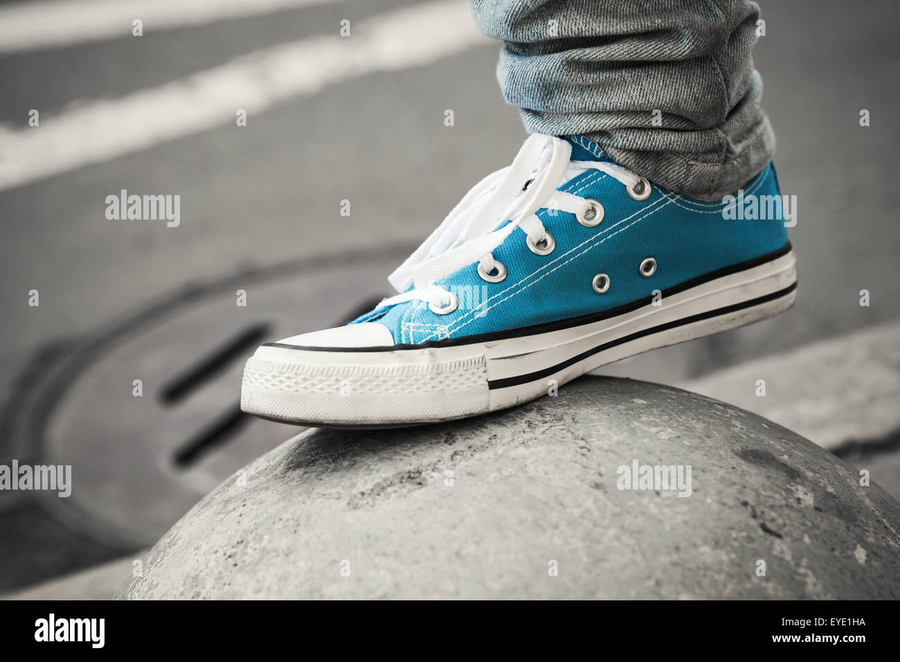 Blue sneaker, teenager foot in urban environment. Closeup photo with selective focus and shallow DOF Stock Photo