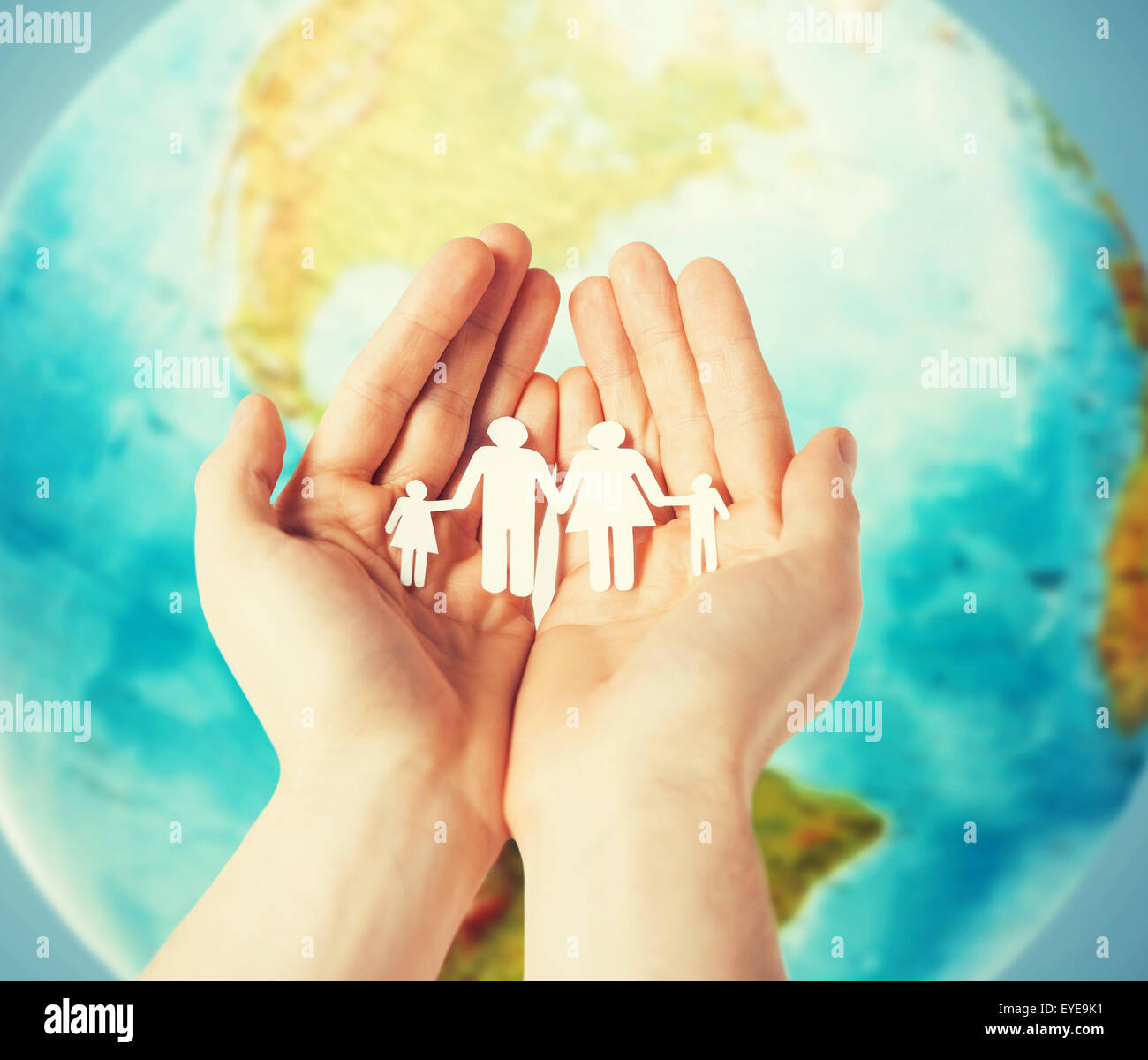 human hands holding paper family over earth globe Stock Photo