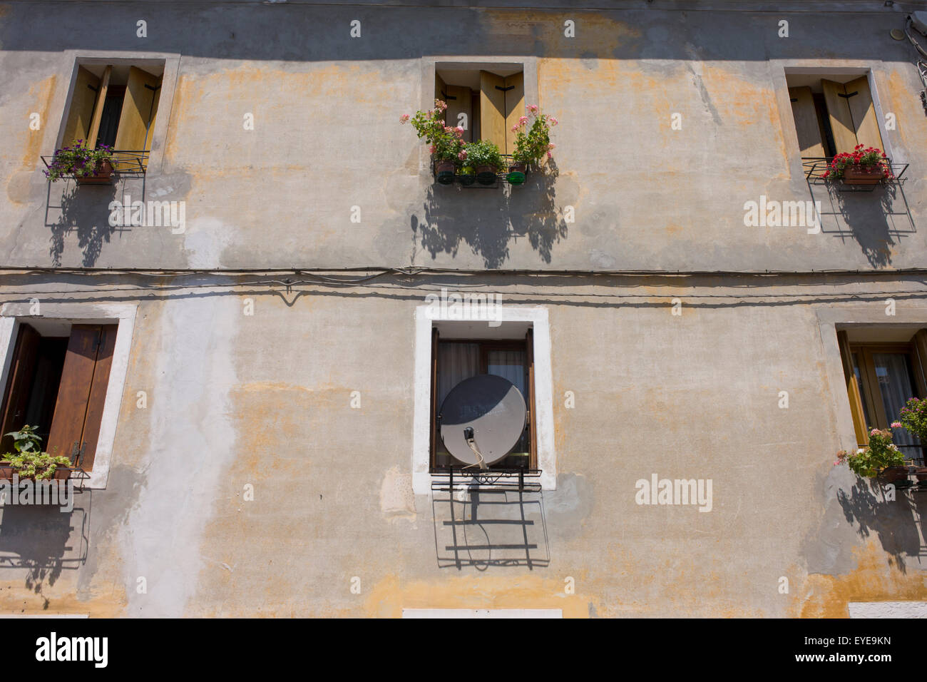 A satellite dish takes up the space of an Italian home's window. Stock Photo